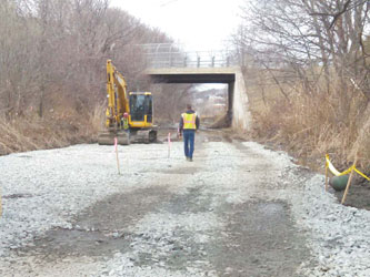 A worker walks the rail bed near Cottage Street this week, a rail bed that is now being transformed into an extension of the bus rapid transit Silver Line. The long-awaited project began construction last week.