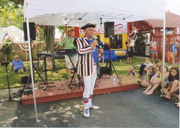 Party organizer Artie Ells, attired in his traditional red, white and blue costume, speaks to the many guests at the annual July Fourth celebration.